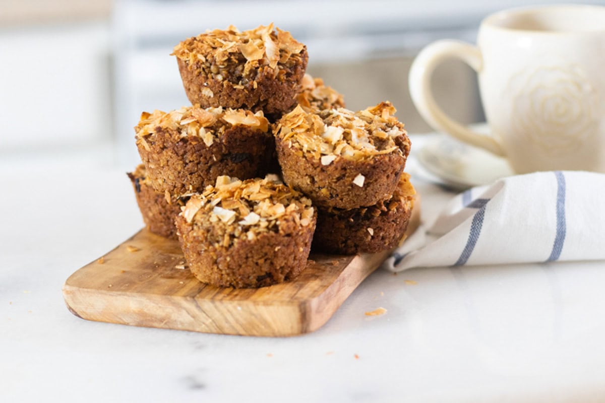 Applesauce muffins stacked, rested on wooden board.
