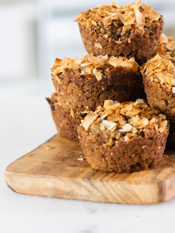 Tall stack of sugar free applesauce muffins on a wooden cooling board.