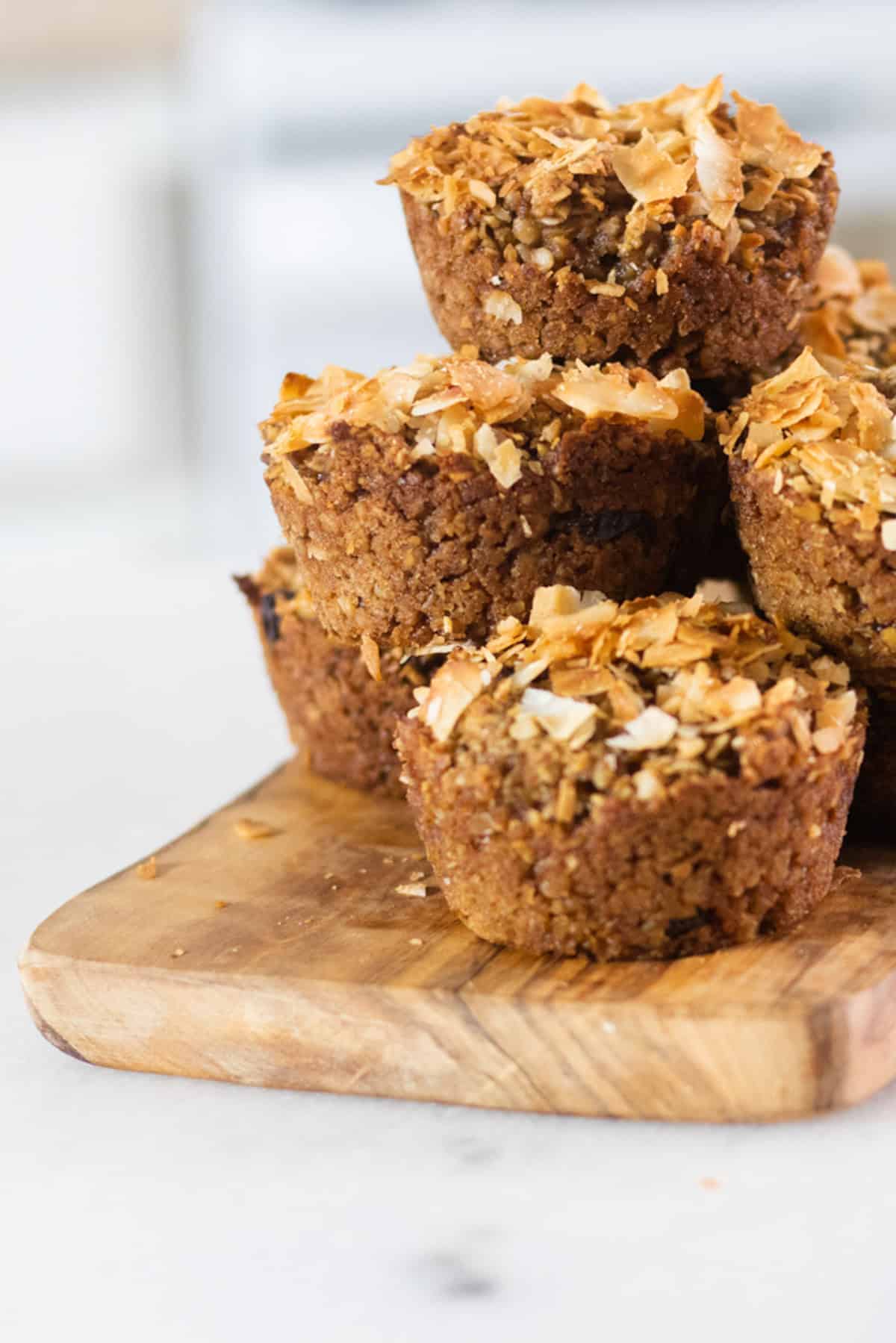 Applesauce muffins stacked, resting on a wooden board.