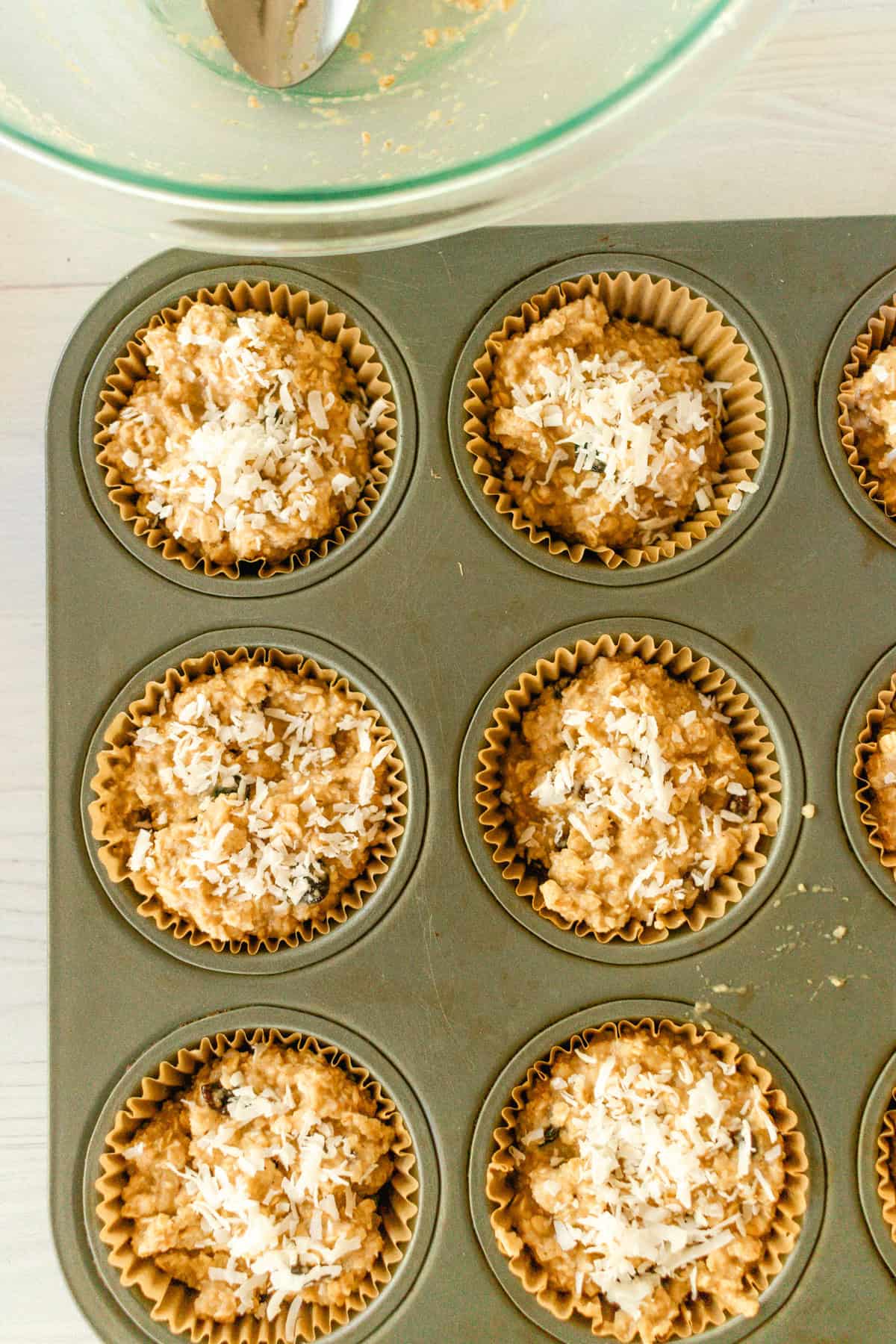 Scooping the batter into muffins tins and sprinkling coconut flakes on top. 