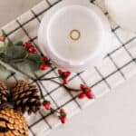 Looking down on a diffuser, red berries, and pinecones on a plaid towel.
