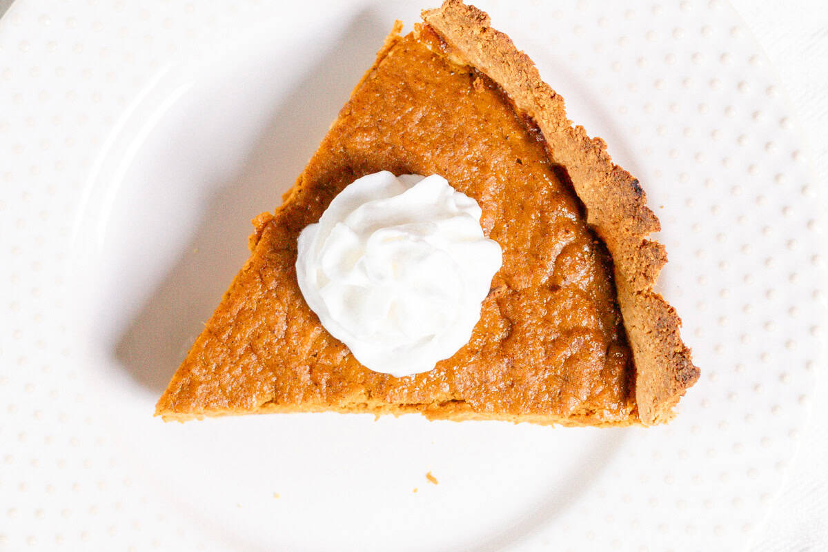 A slice of healthy pumpkin pie with coconut whipped cream on top.