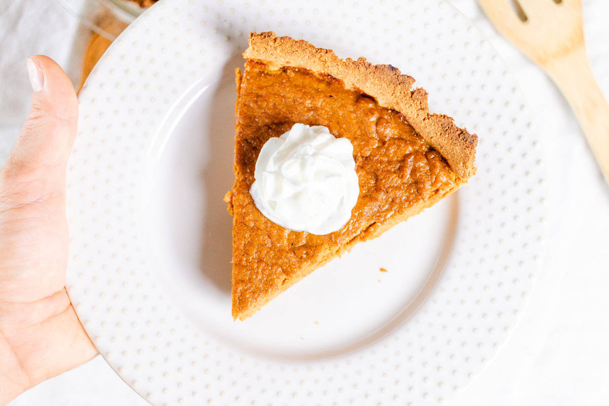A slice of pumpkin pie with whipped cream on top.