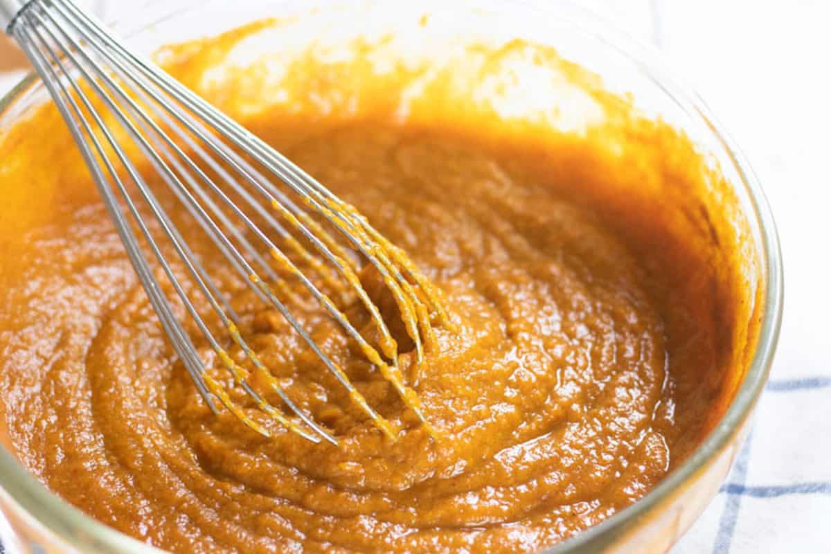 Mixing healthy pumpkin pie filling in a glass mixing bowl.