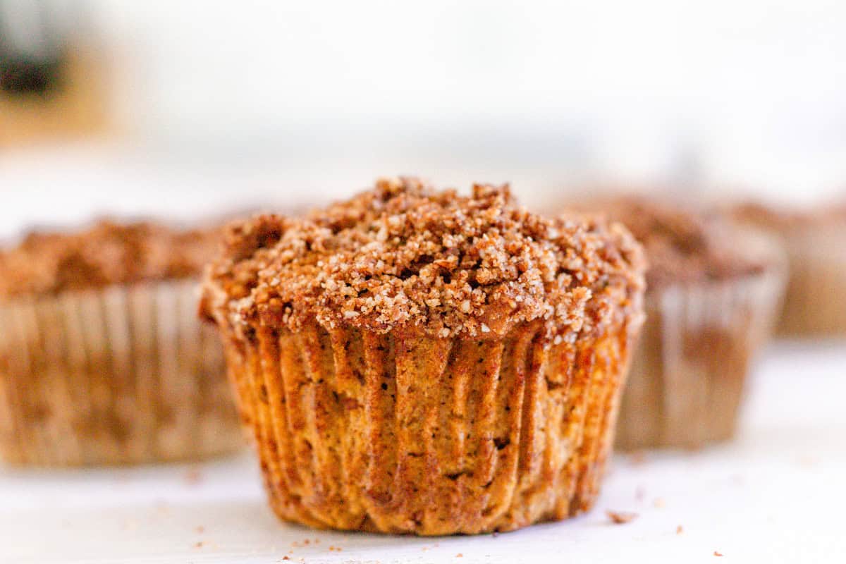 A healthy pumpkin muffin with a cinnamon sugar crumble sitting on a white table. 