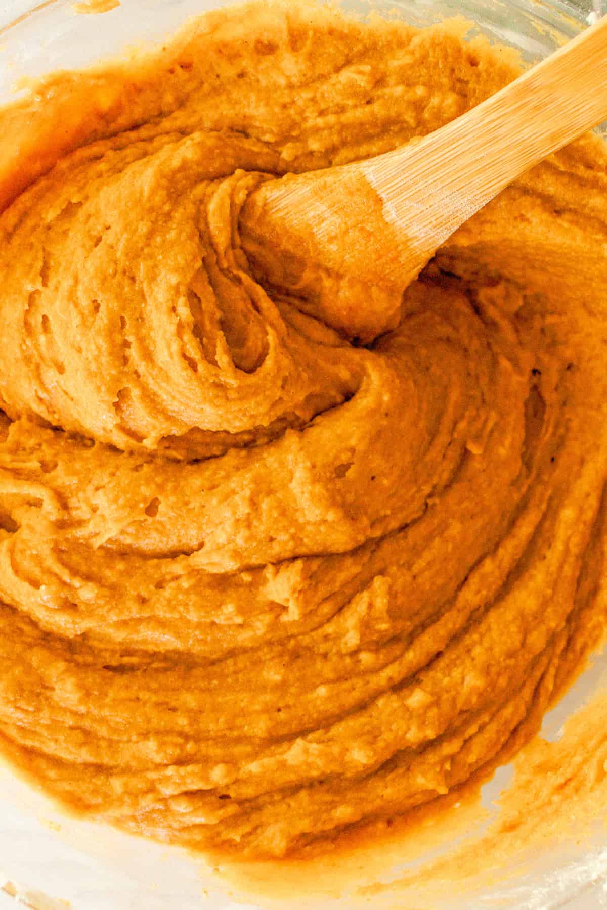 Combining the wet and dry ingredients for the healthy pumpkin muffins in a large mixing bowl.