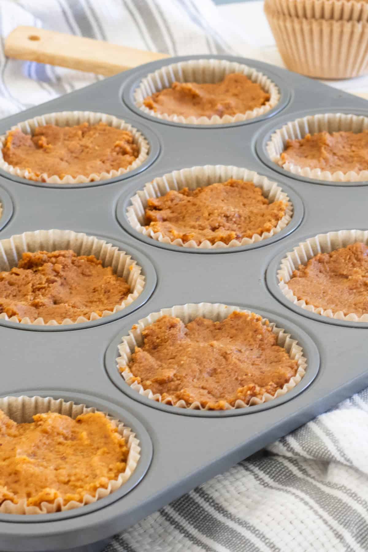 The muffin batter in a muffin tins with sleeves.