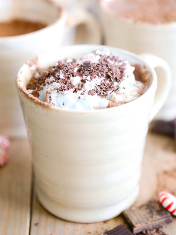 A mug of paleo peppermint hot chocolate with whipped cream and chocolate shavings on top.