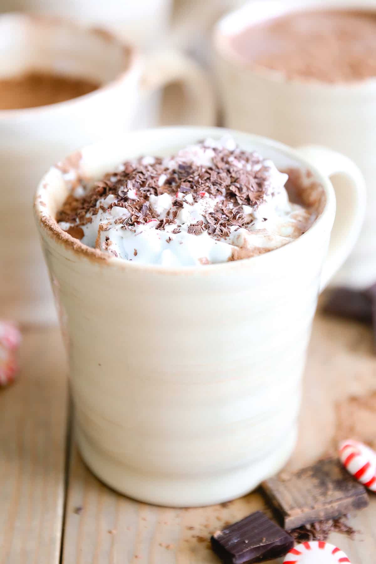 A mug of paleo peppermint hot chocolate with whipped cream and chocolate shavings on top.