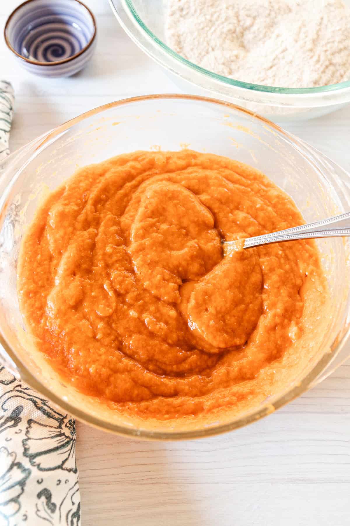 Mixing together the wet ingredients for the pumpkin bread in a glass mixing bowl. 