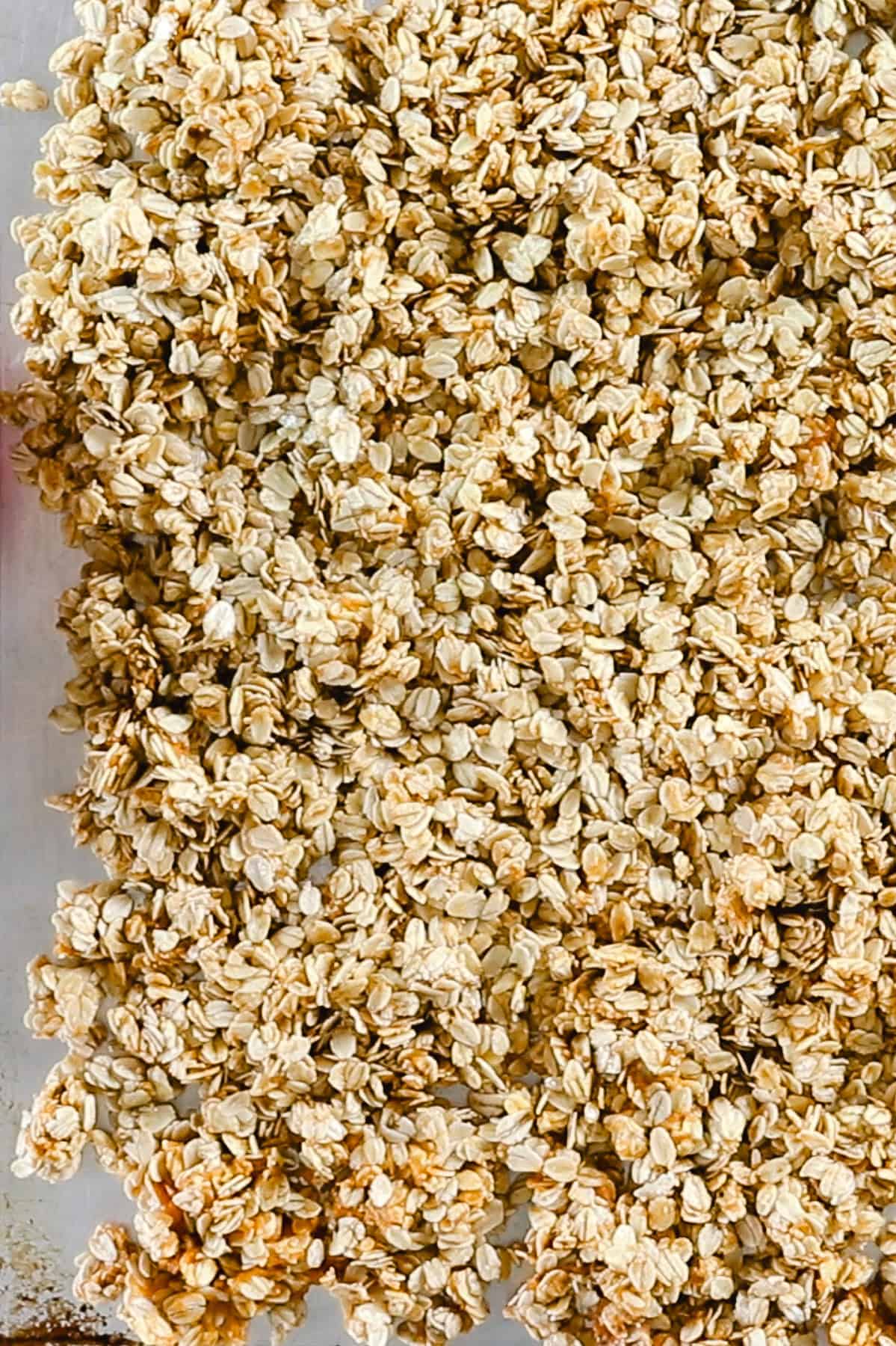 Spreading pumpkin granola on a sheet pan to bake.