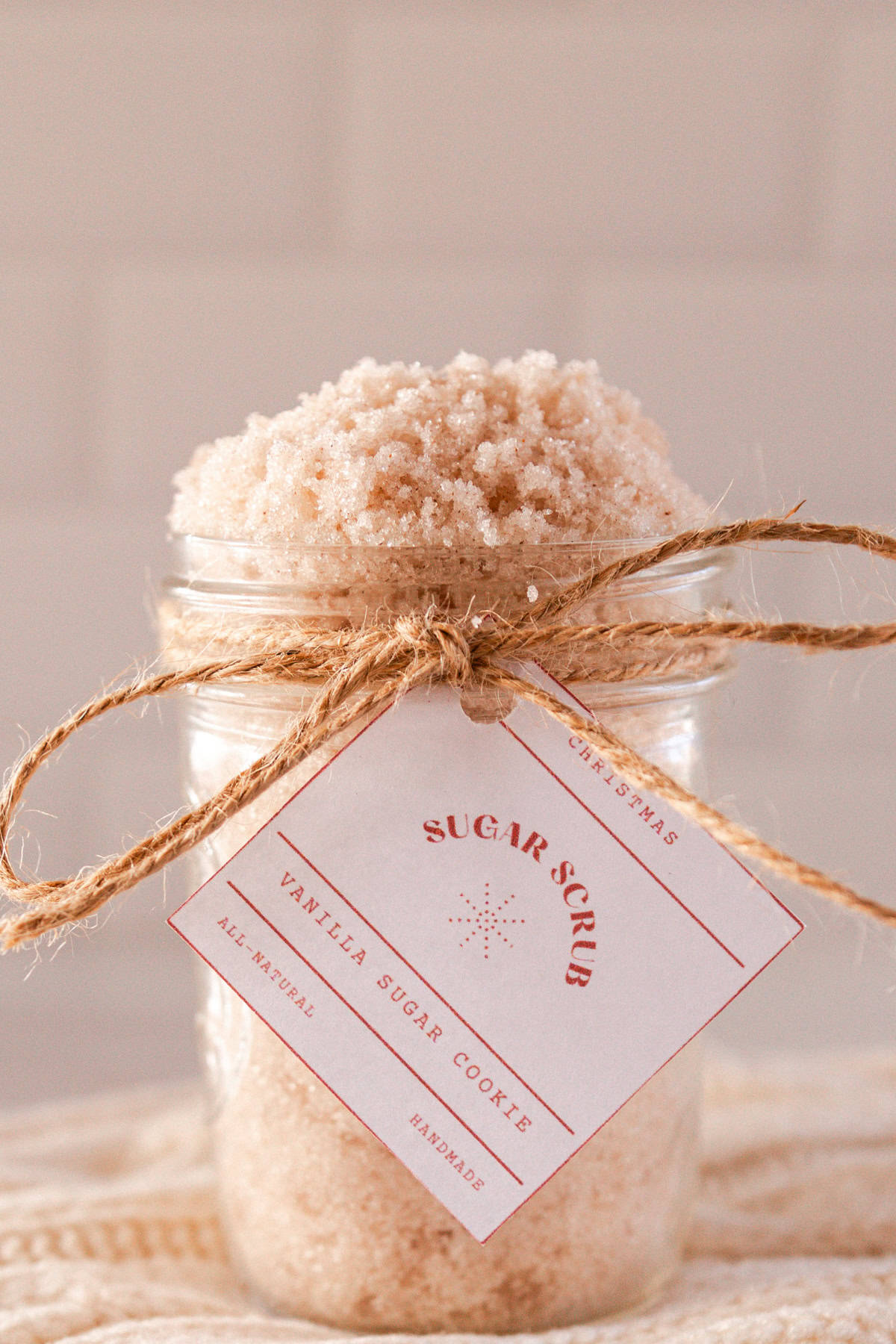 A jar of sugar cookie scrub with a label tied on with twine.
