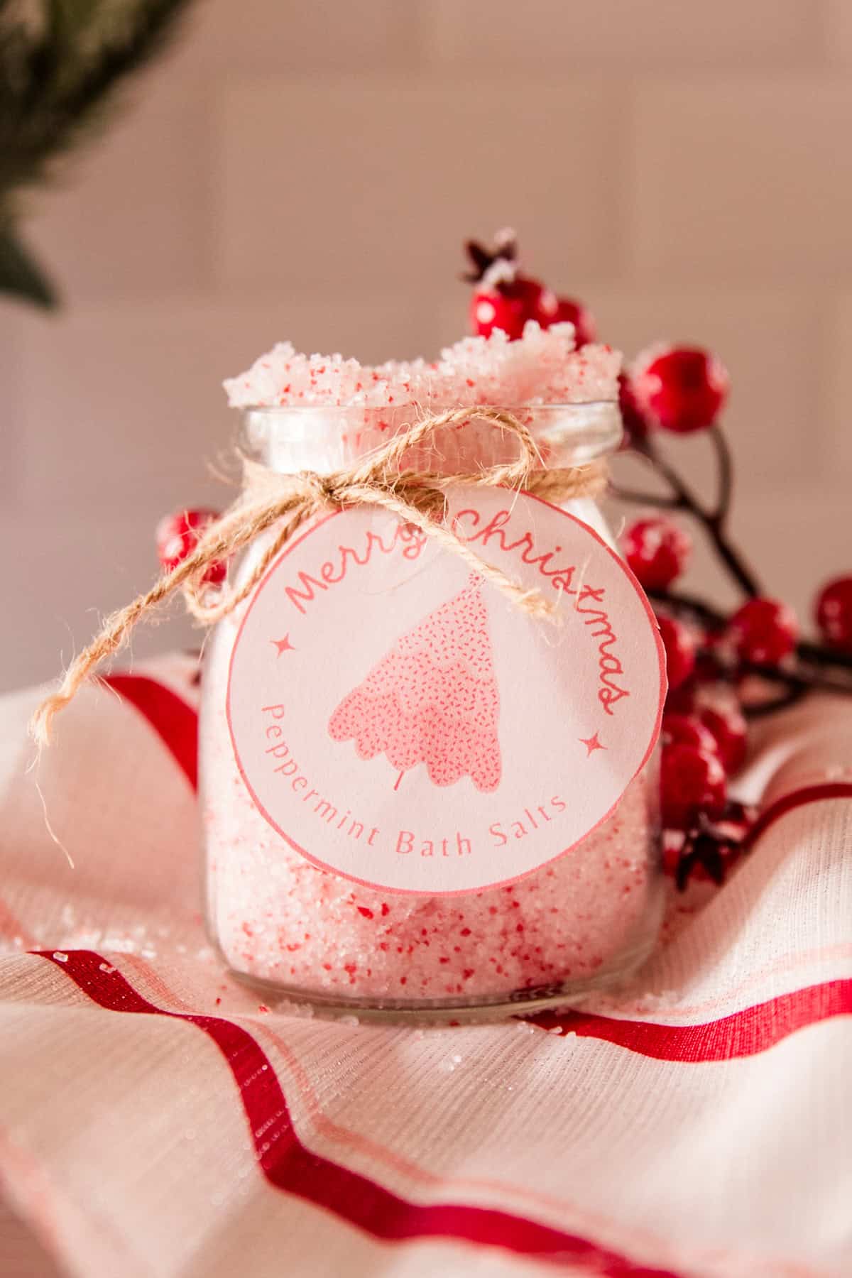 A jar of peppermint bath salts with a homemade label and red berries.