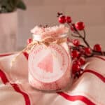 DIY peppermint bath salts in a clear jar on a christmas striped tea towel.