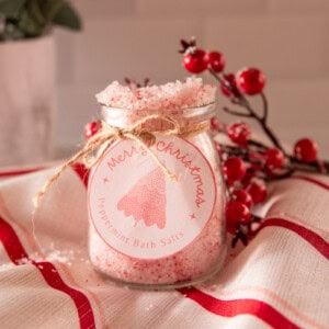 DIY peppermint bath salts in a clear jar on a christmas striped tea towel.