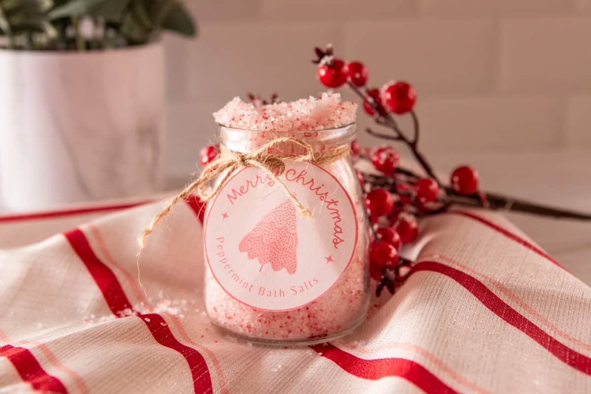 DIY peppermint bath salts in a clear jar on a christmas striped tea towel.