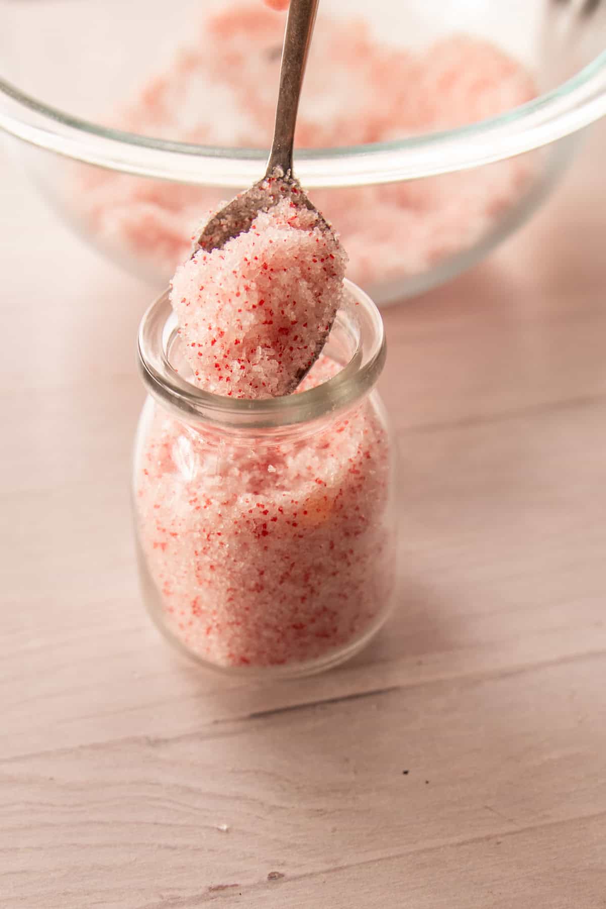 Pouring peppermint bath salts into a glass jar. 