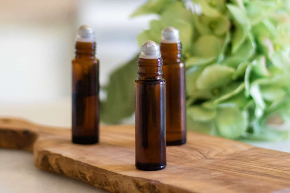 Several roller balls of essential oils on a wooden platform. 