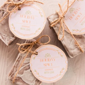Holiday spice soap with handmade labels tied to them with hemp string on a wooden tabletop.