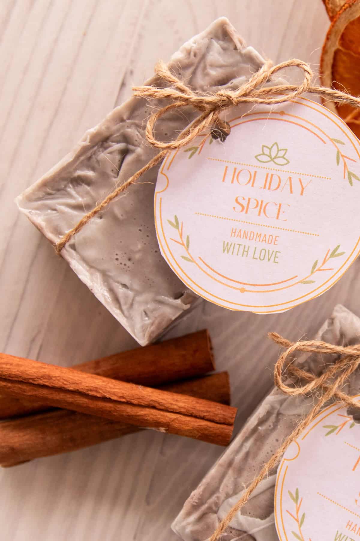 A finished holiday spice soap bar with a holiday tag and cinnamon sticks.