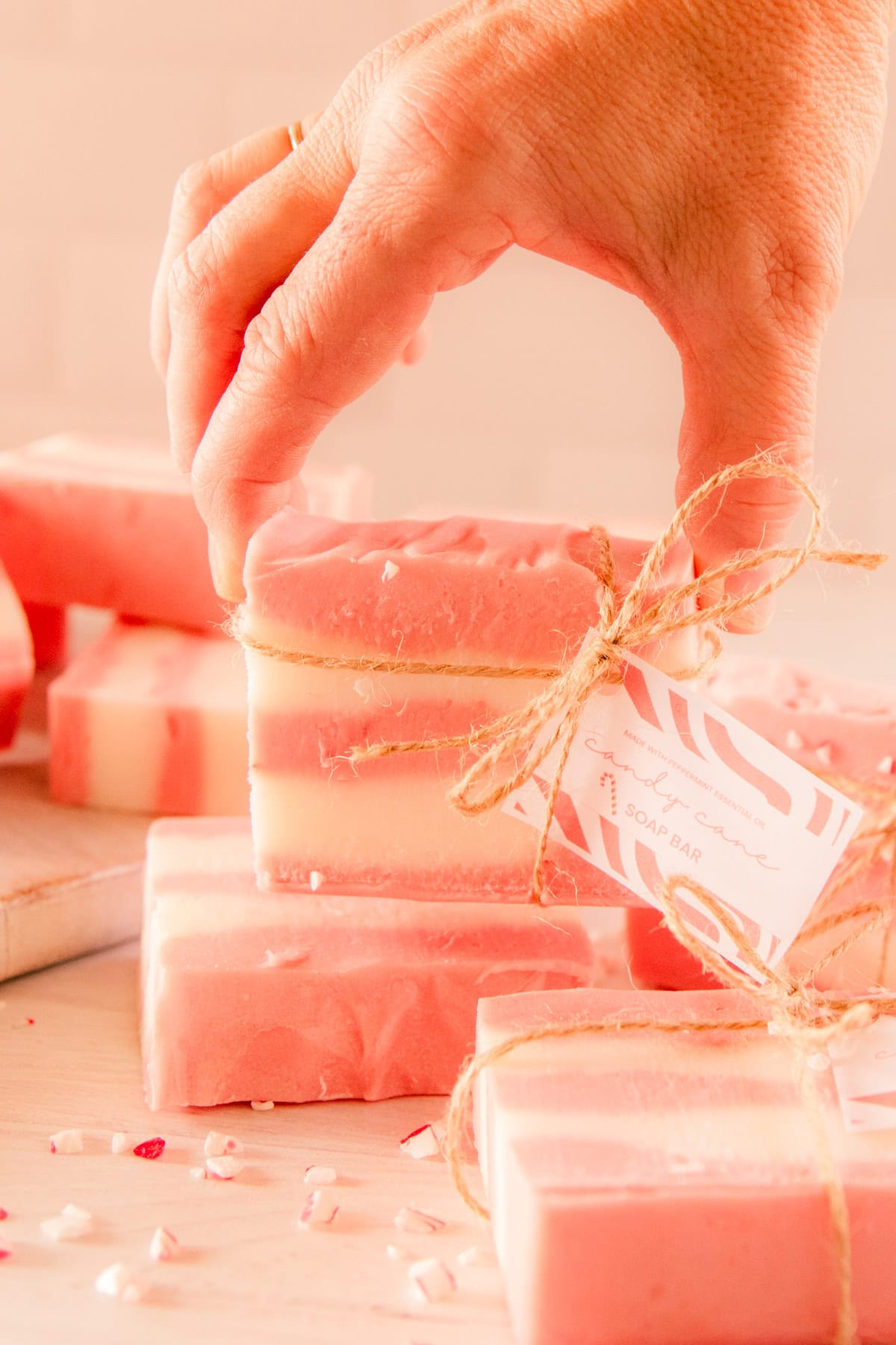 Holding up a bar of candy cane soap tied with twine and a gift tag.