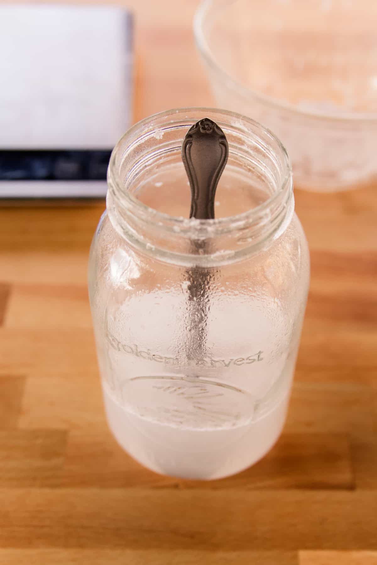 Lard and water mixed in a mason jar with a metal spoon.
