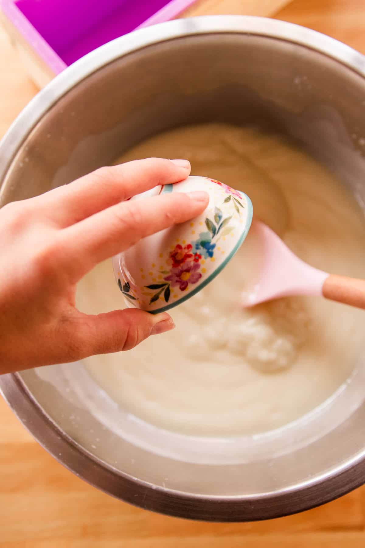 Pouring essential oil into to soap mixture in a mixing bowl.