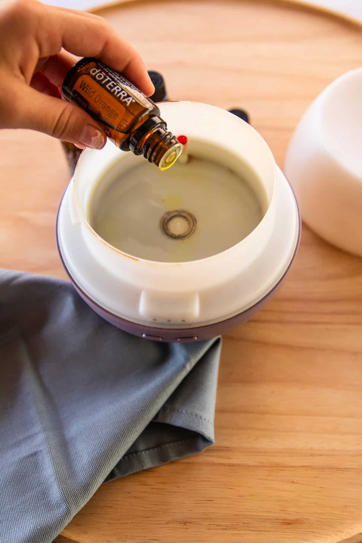 Adding drops of essential oils into a diffuser filled with water.