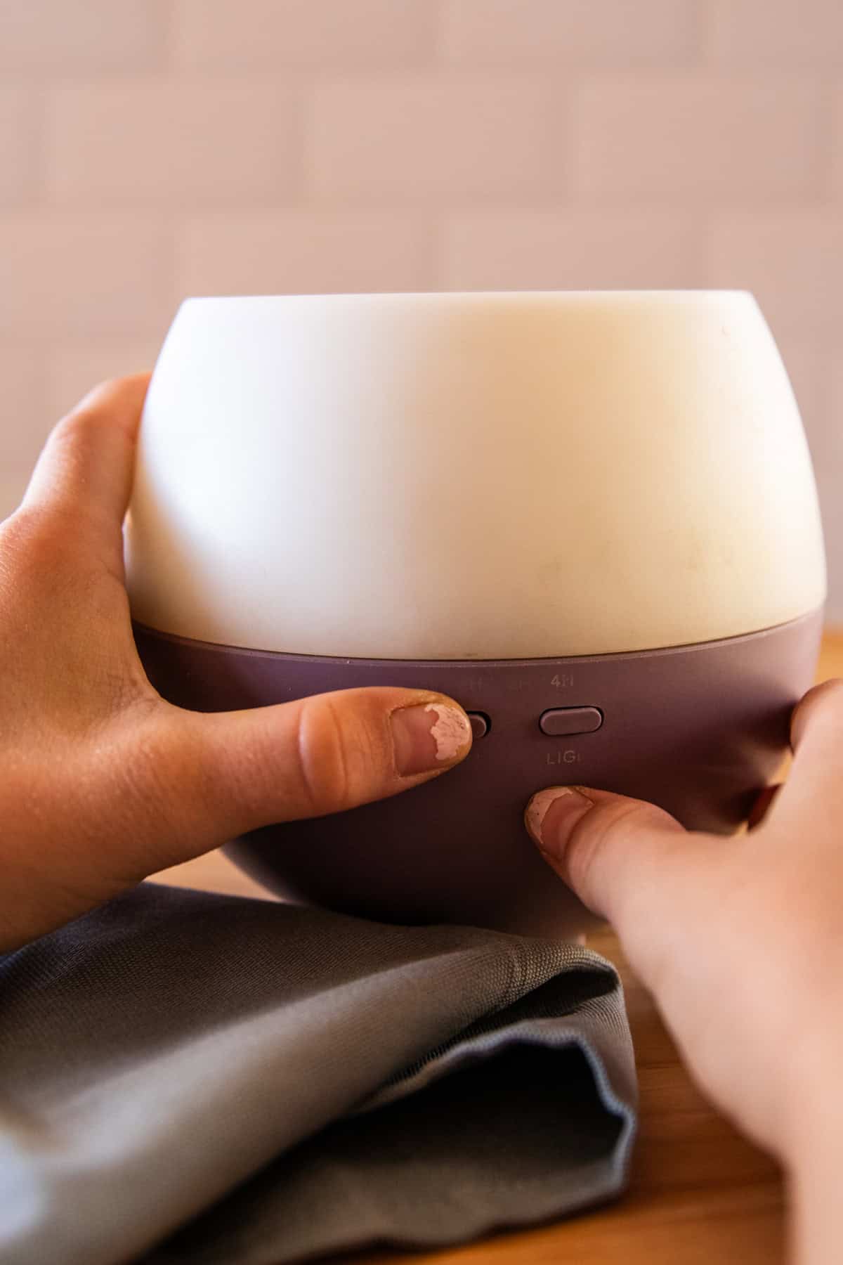 Pressing the start button on an essential oil diffuser.