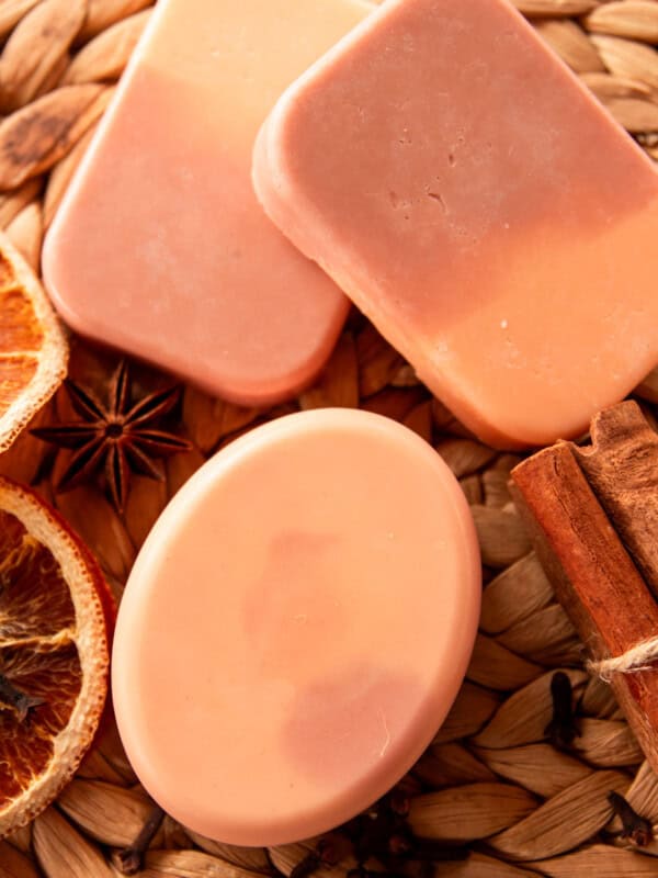 Three bars of orange creamsicle soap with dried orange slices and cinnamon sticks.