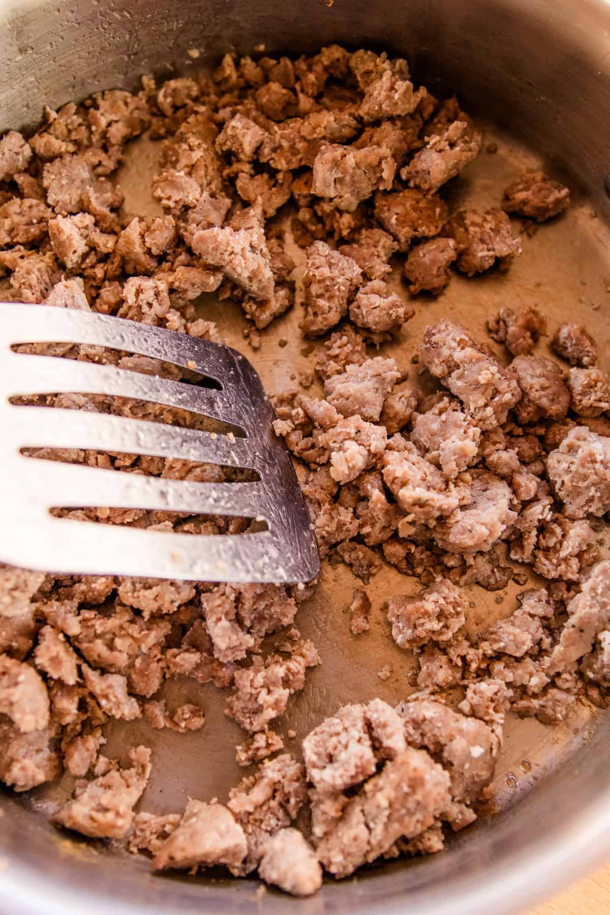 Browning sausage in a cast iron skillet.