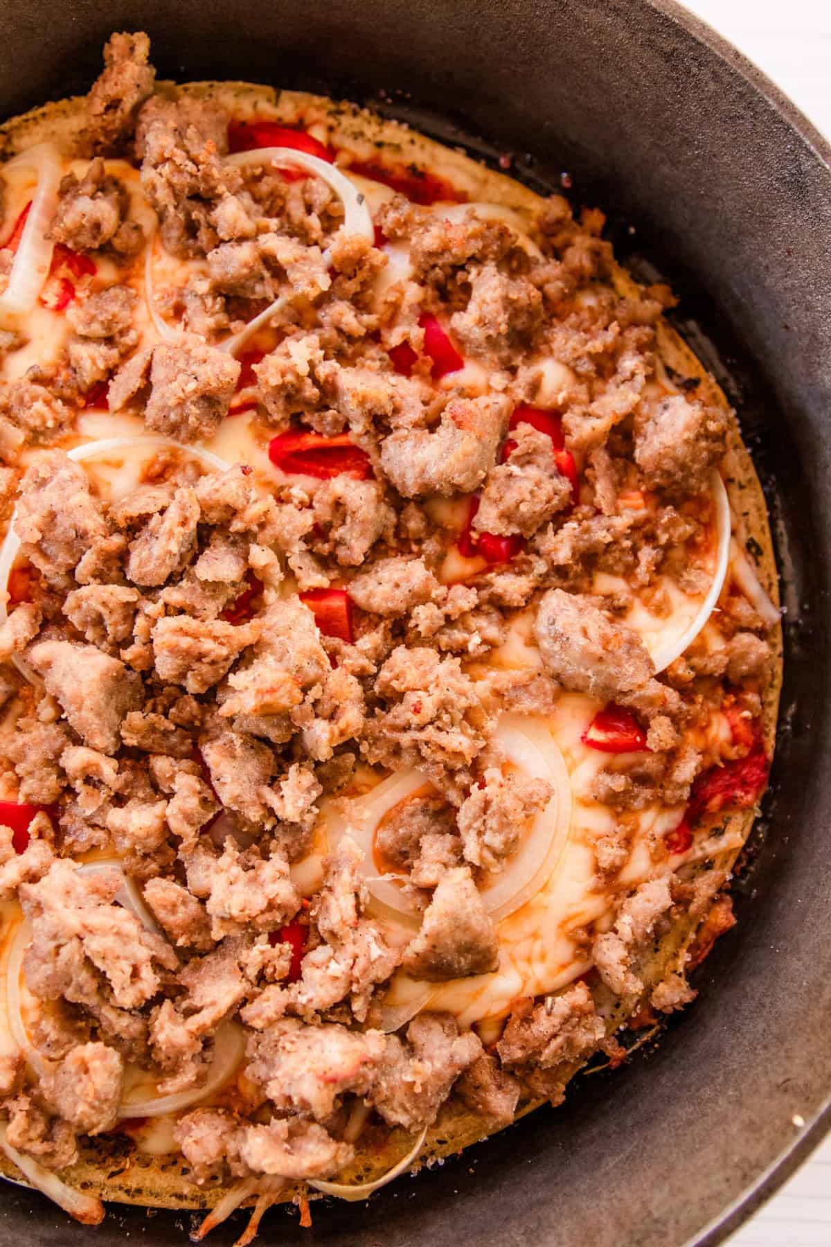 A sausage sourdough pizza in a cast iron skillet.