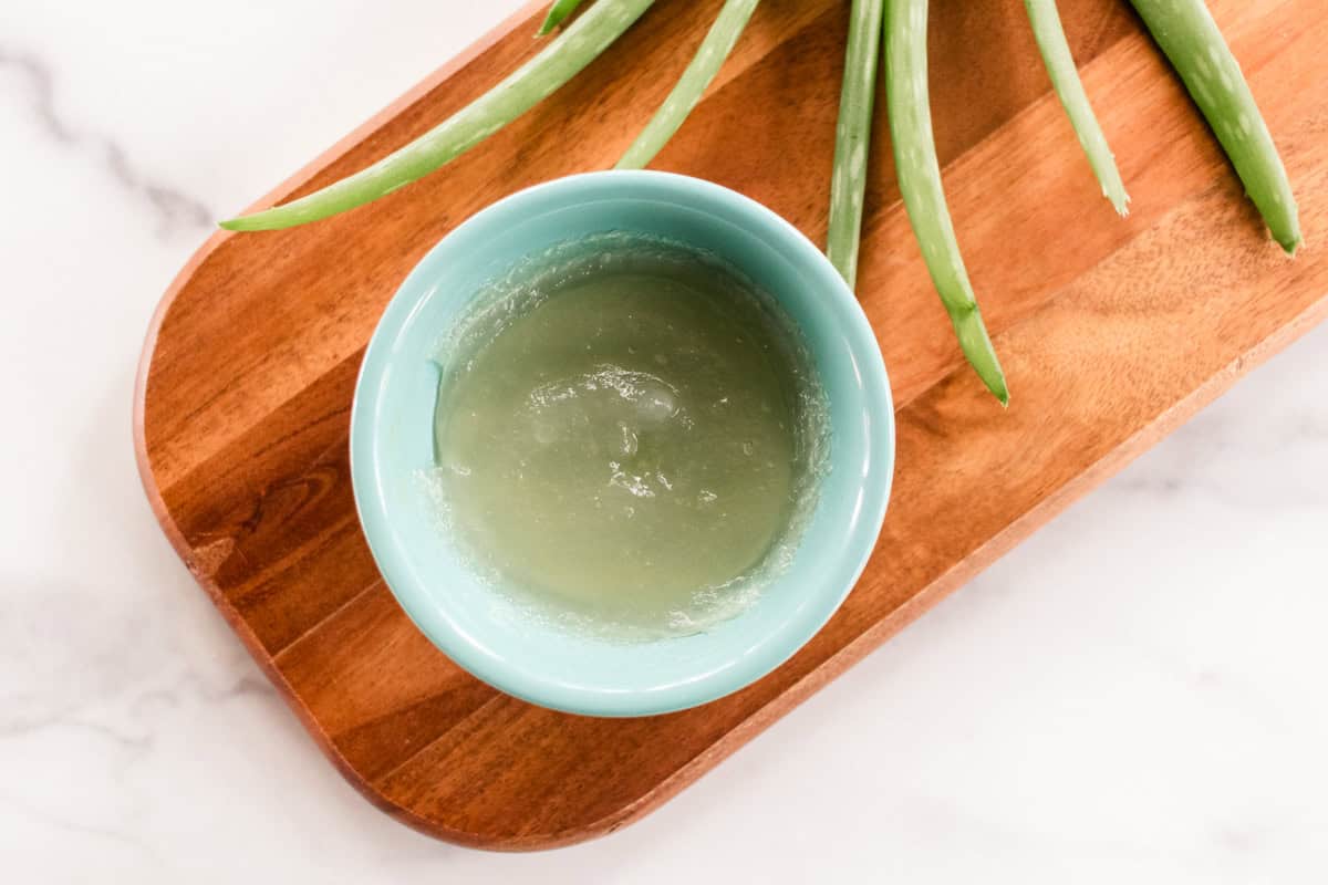 A bowl of aloe vera on a wooden board.