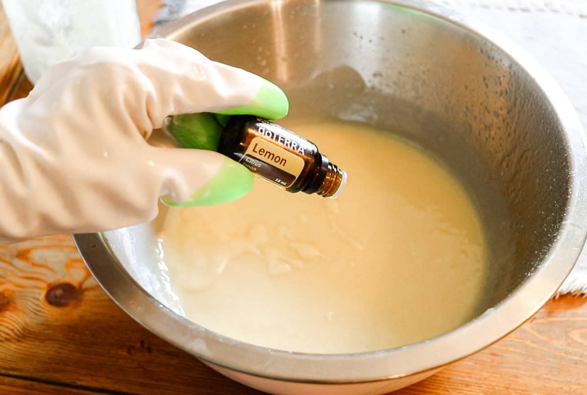 Dropping lemon essential oil into a bowl of soap mixture.