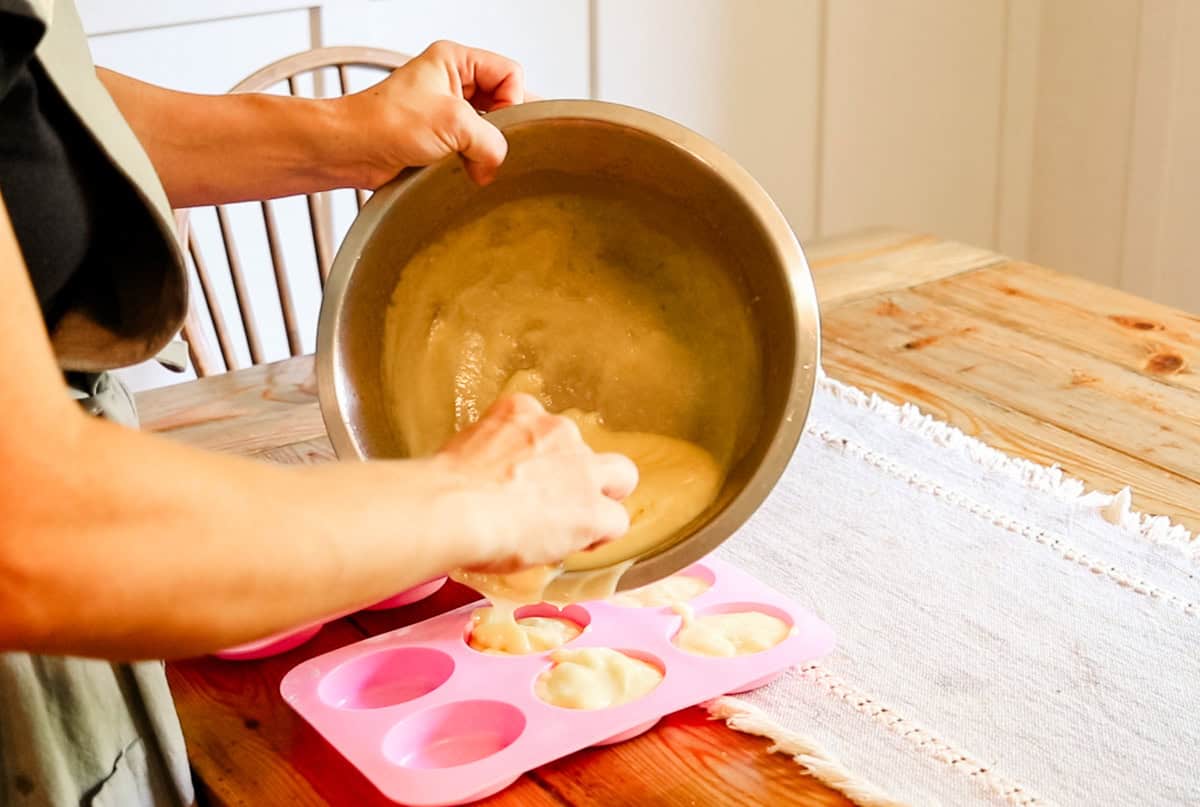 Pouring soap mixture into pink silicone soap molds.