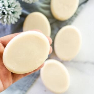 Holding a coconut milk soap bar over a marble vanity.