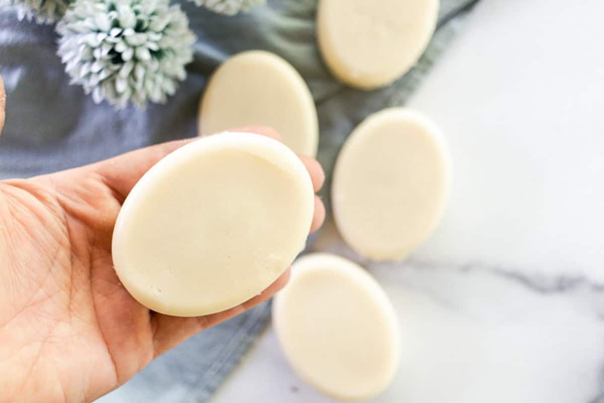 Holding a coconut milk soap bar over a marble vanity.