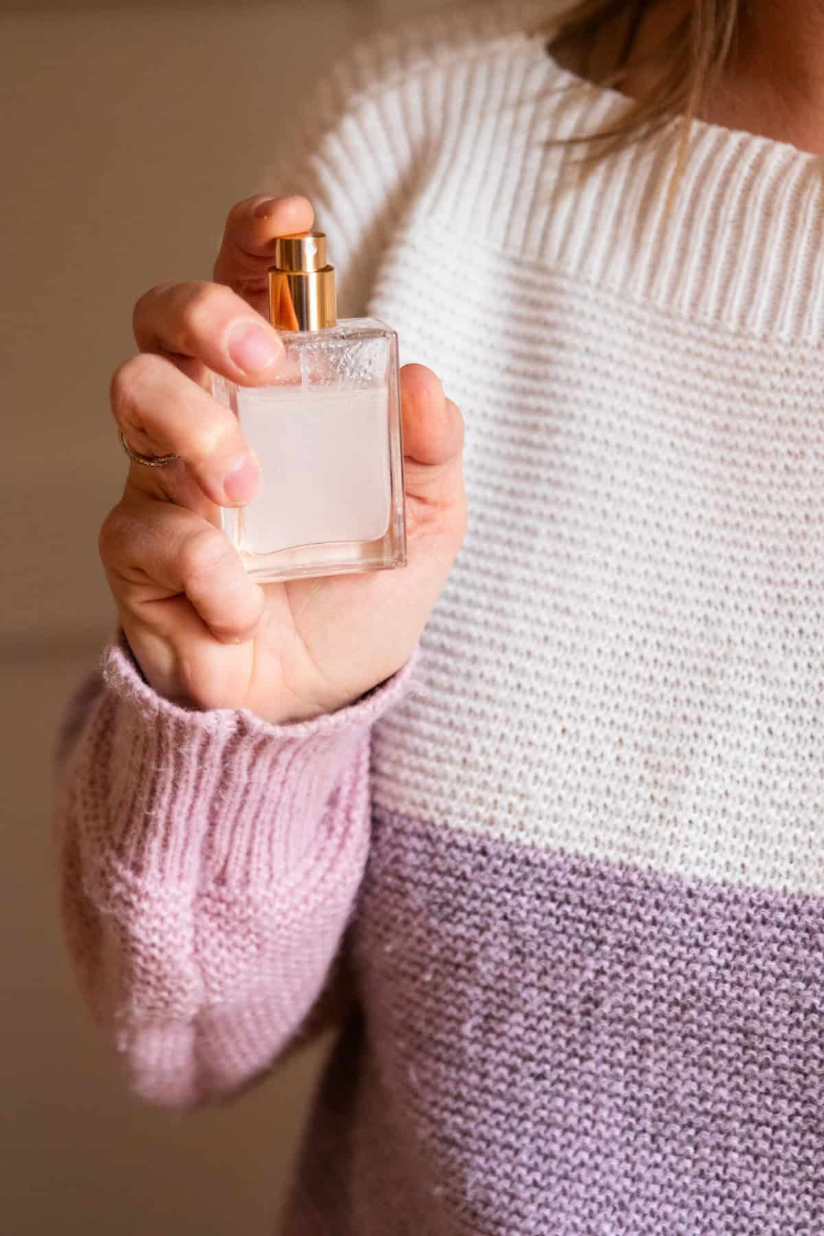 Spraying natural perfume from a glass bottle.