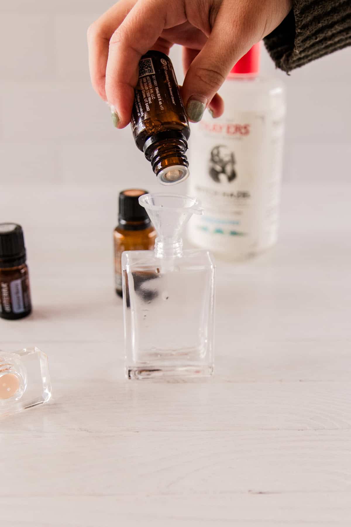 Dropping essential oils into a glass perfume bottle.