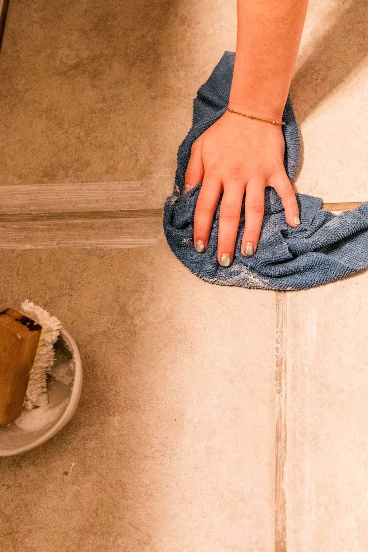 Wiping a grout line with a microfiber cloth.