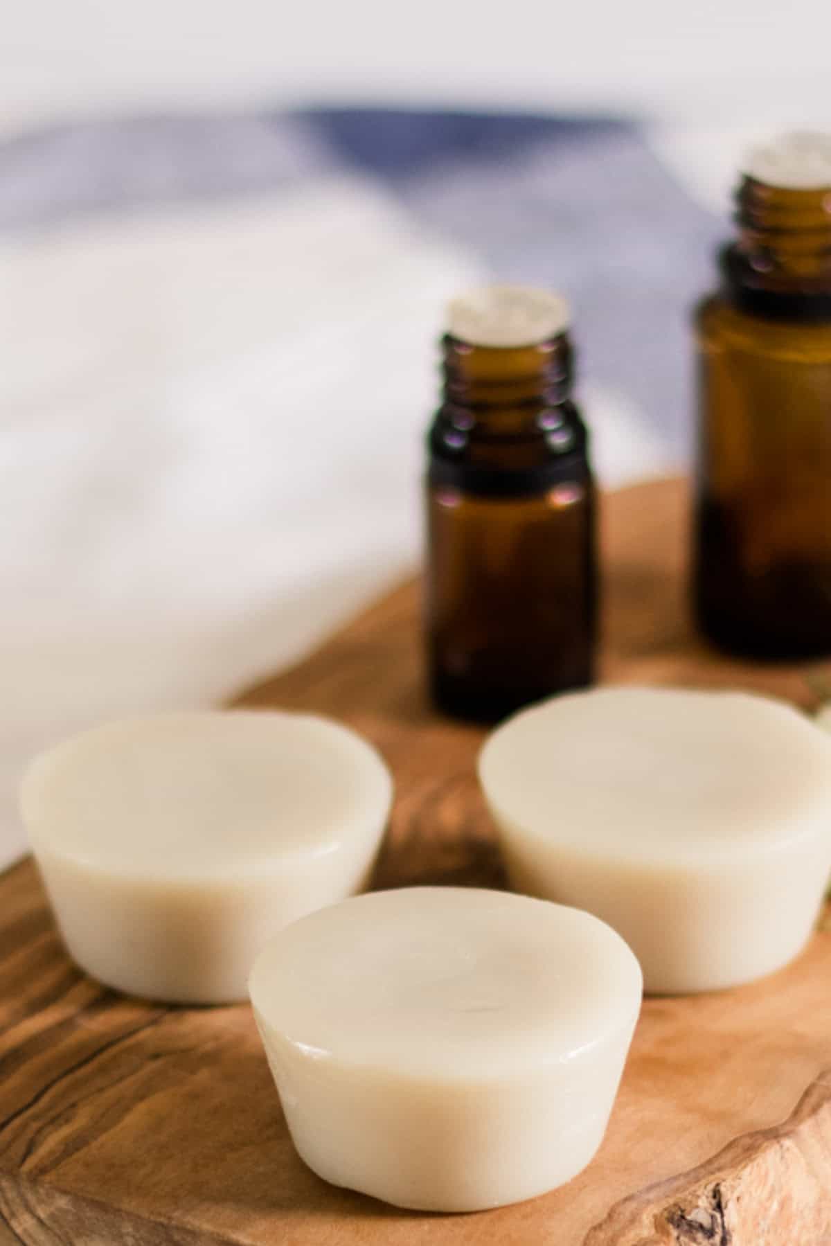 Muscle rub lotion bars on a wooden board with essential oil bottles.