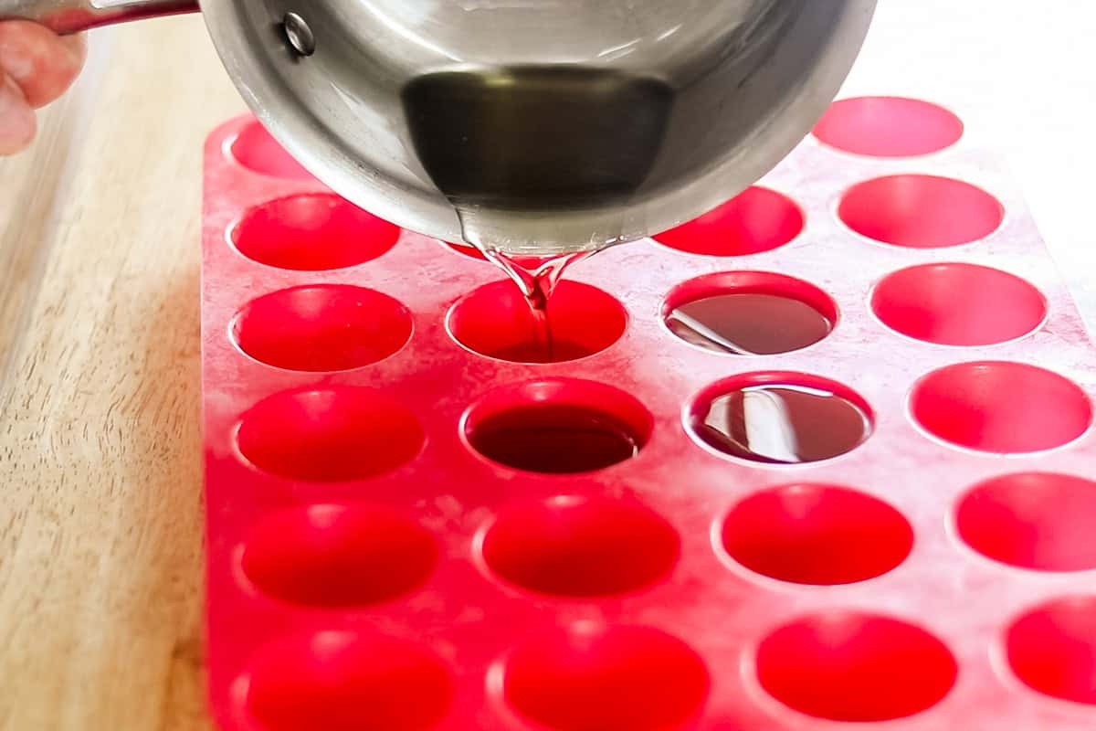 Pouring melted muscle rub mixture into silicone molds.
