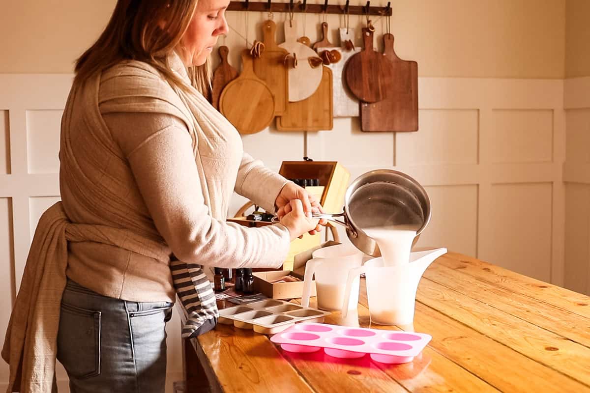Transferring melted soap base into two plastic pitchers.