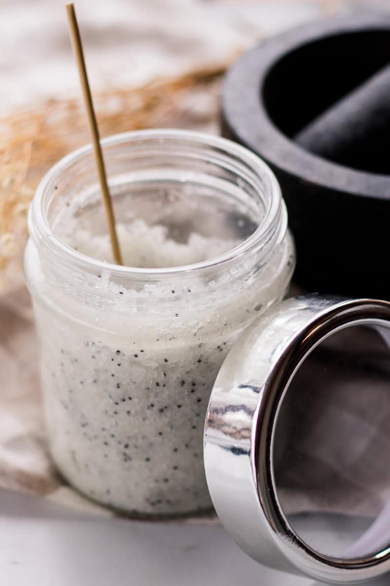 A jar of dead sea salt scrub with dried flowers.