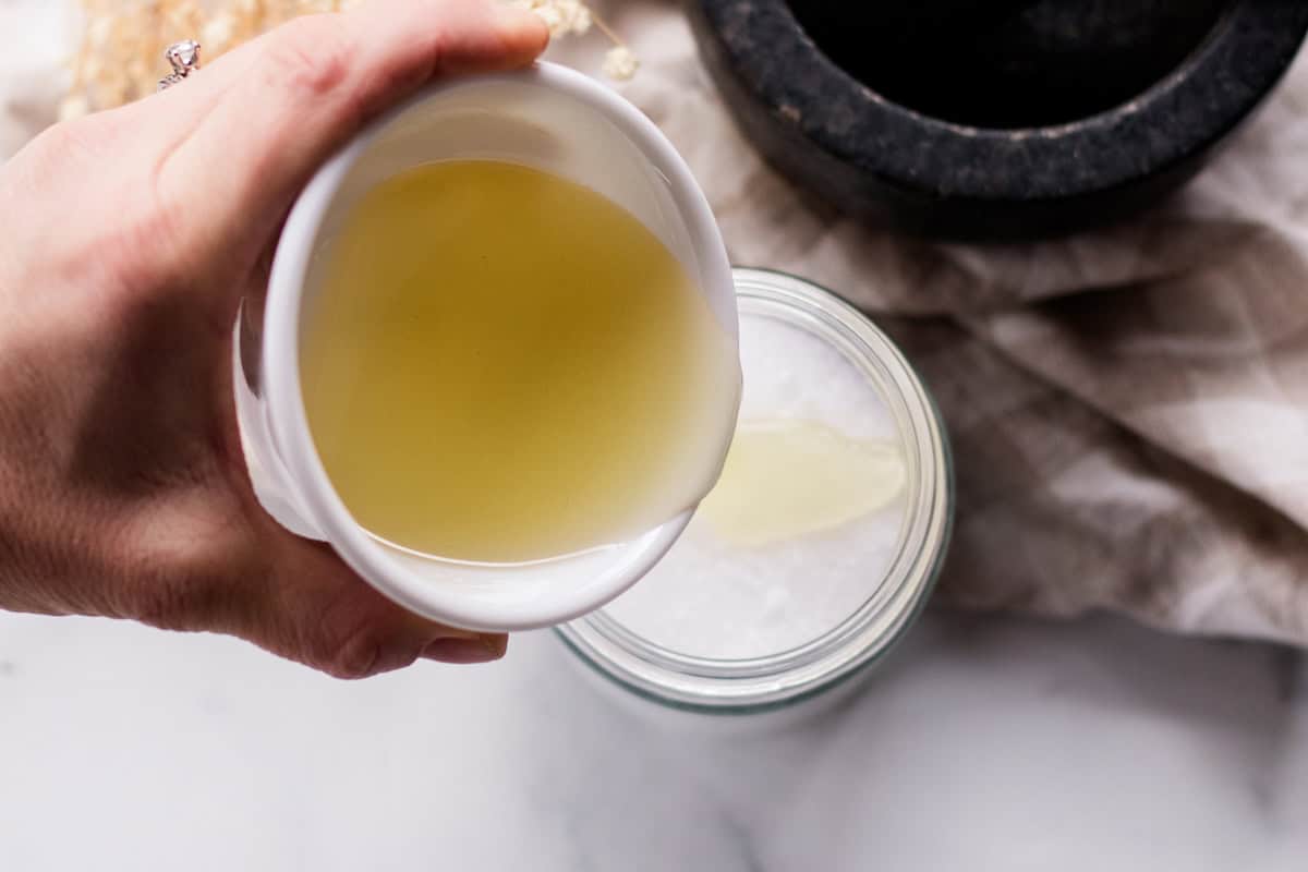 Pouring melted oil into a jar full of sea salt.