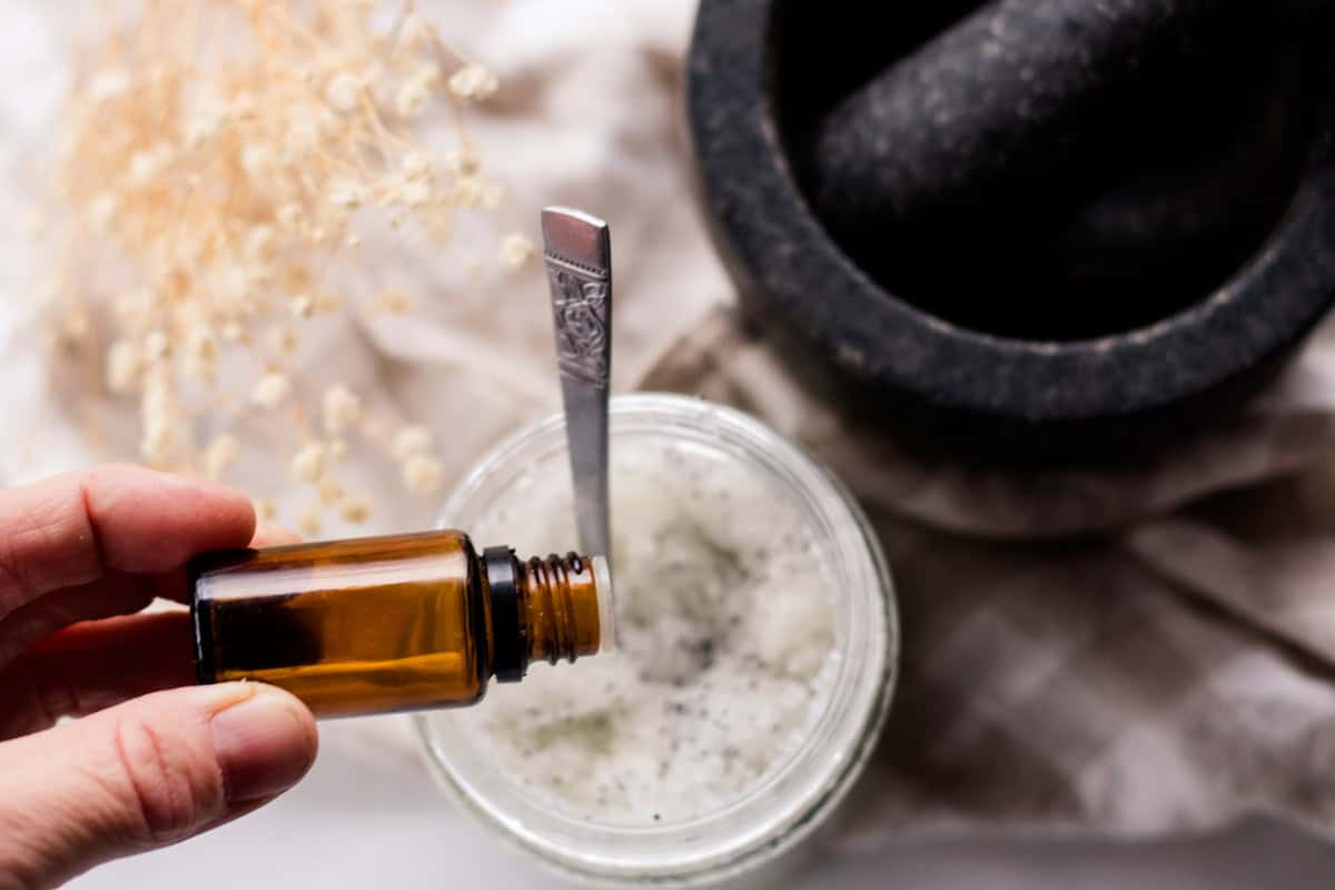 Adding essential oil drops into a jar of sea salt scrub.
