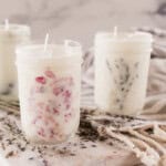 Three mason jar candles on a white table with dried lavender;