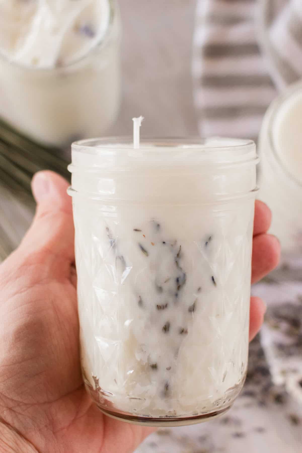 Holding a mason jar candle with dried lavender flowers.