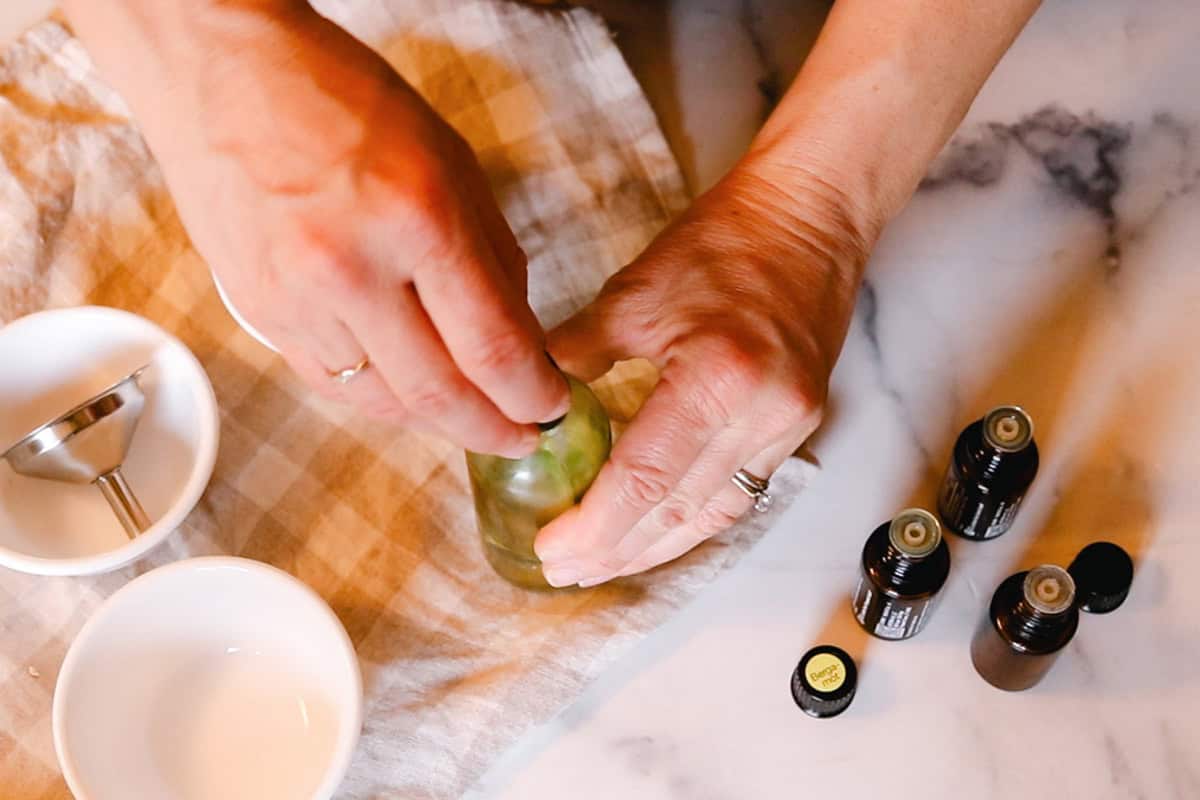 Securing a lid on a glass spray bottle of whole body deodorant.