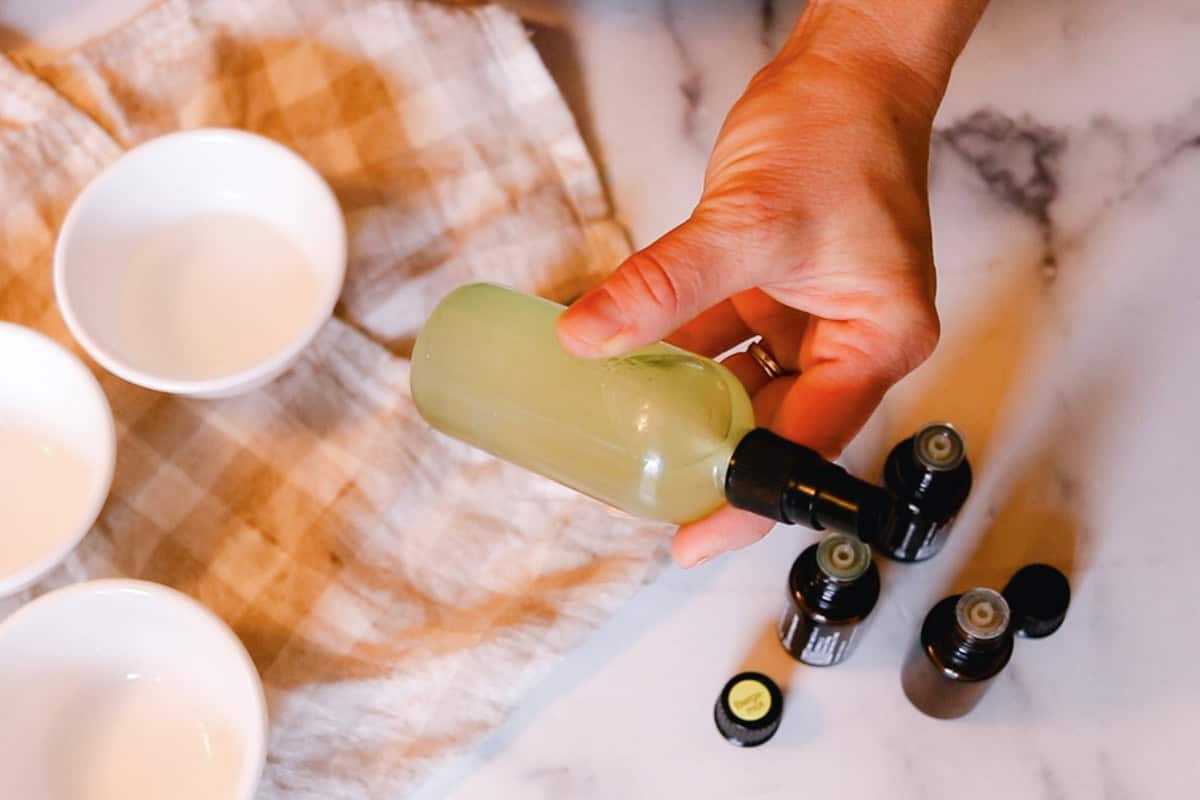 Shaking the bottle of whole body deodorant spray.